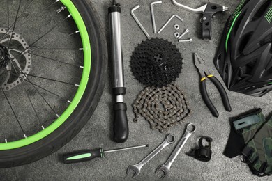 Photo of Parts of bicycle and tools on grey background, flat lay