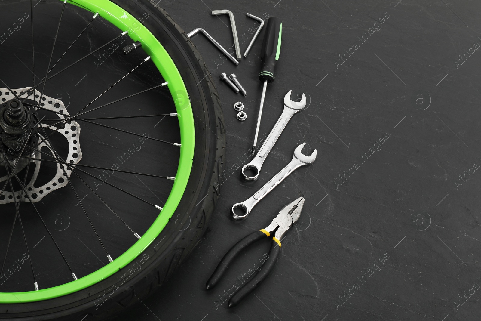 Photo of Bicycle wheel and tools on black background. Space for text