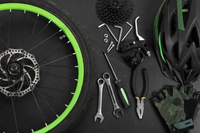 Photo of Parts of bicycle and tools on black background, flat lay