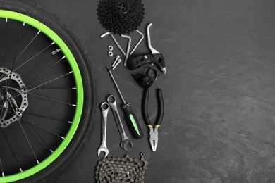 Parts of bicycle and tools on black background, flat lay. Space for text