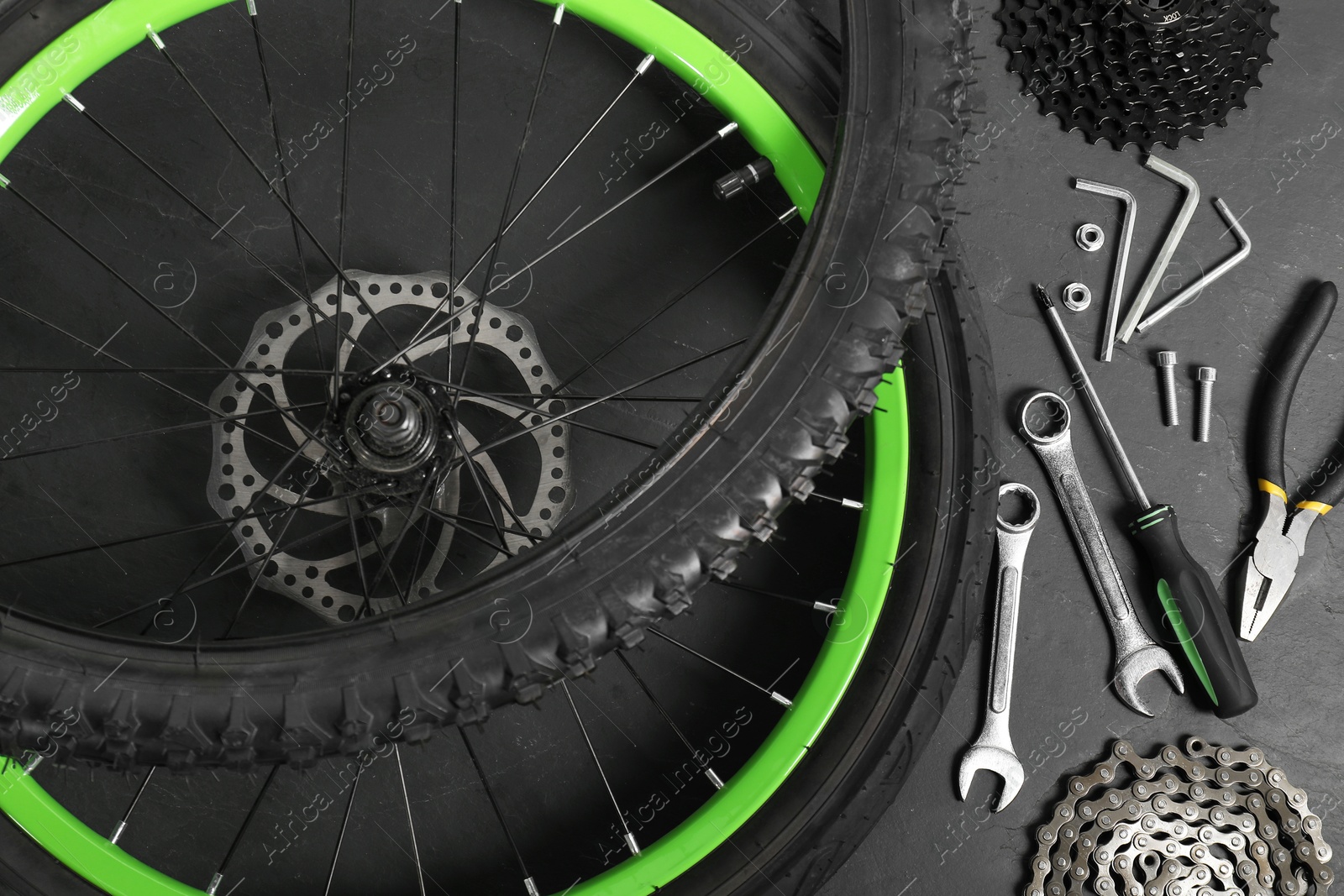 Photo of Parts of bicycle and tools on black background, flat lay