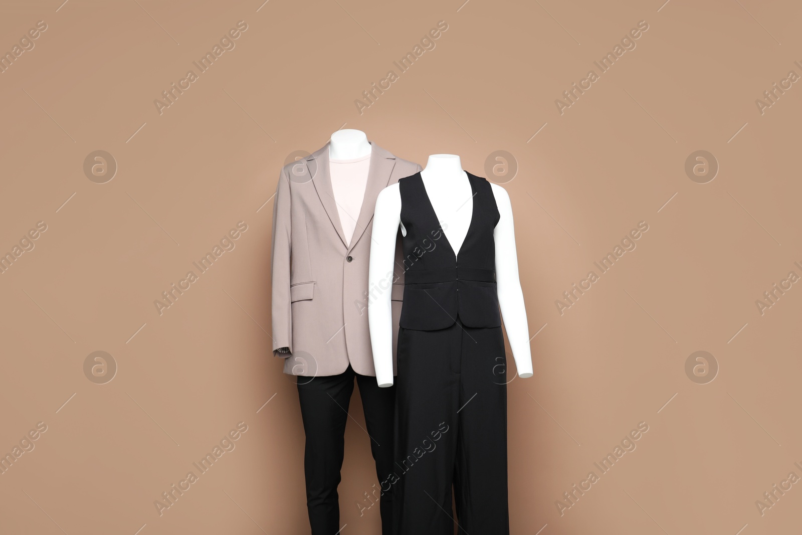 Photo of Female and male mannequins with stylish outfits on light brown background