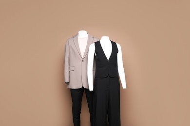 Photo of Female and male mannequins with stylish outfits on light brown background