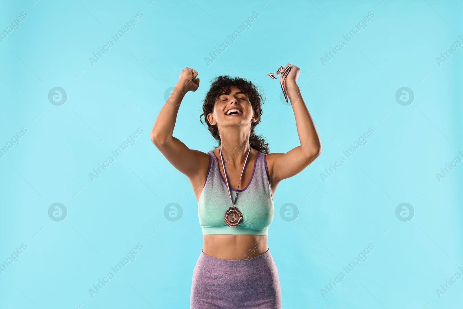 Photo of Happy winner with different medals on light blue background