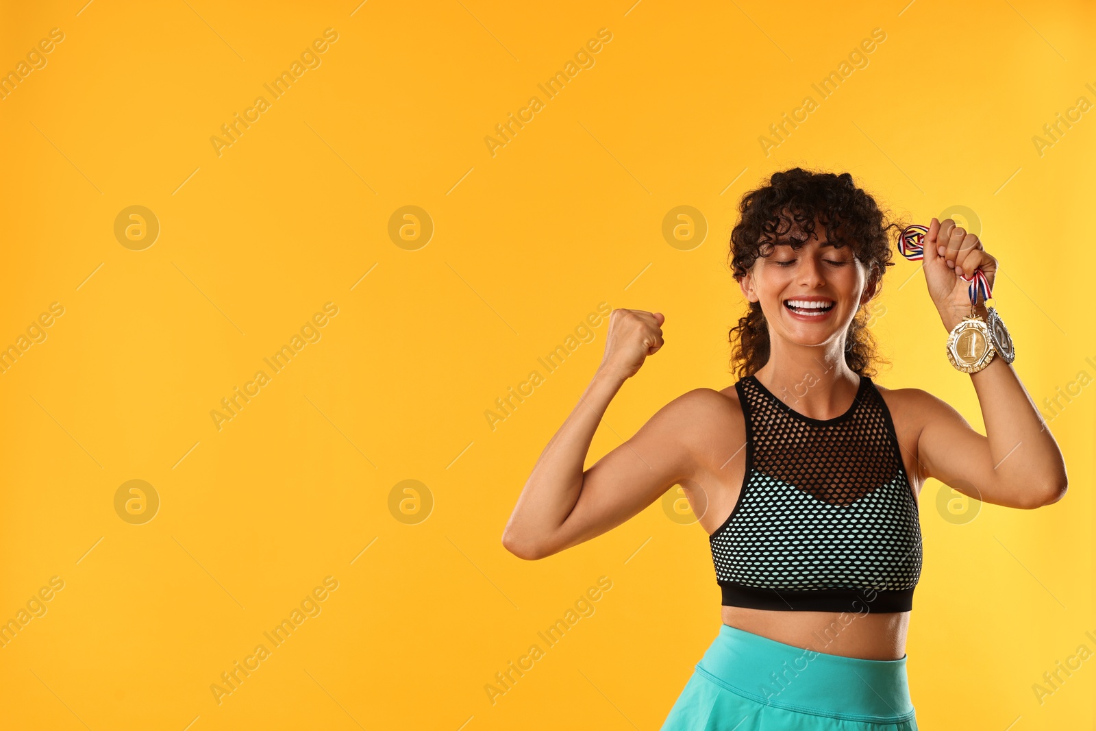 Photo of Happy winner with different medals on yellow background. Space for text