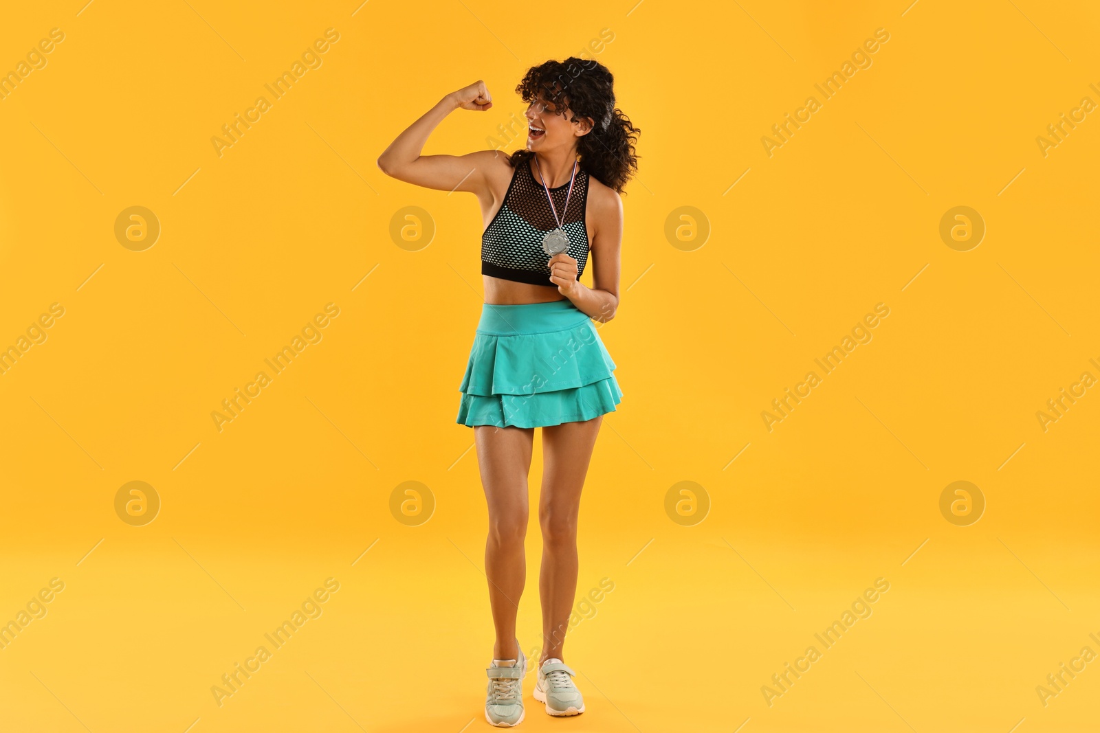 Photo of Happy winner with silver medal showing muscles on yellow background