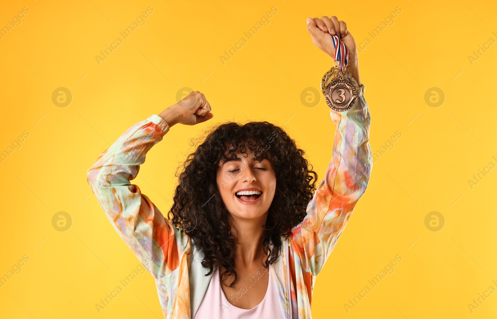 Photo of Happy winner showing different medals on yellow background