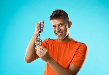 Photo of Happy winner with bronze medal on light blue background