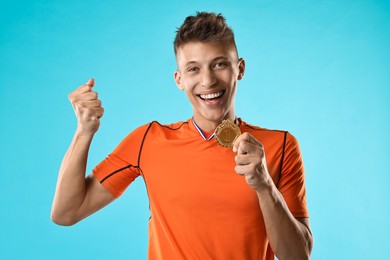 Photo of Happy winner with golden medal on light blue background