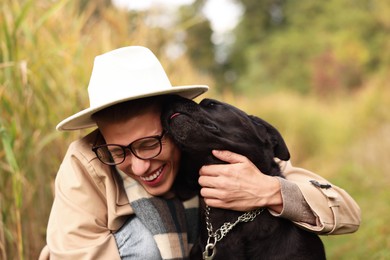 Smiling man hugging cute dog outdoors on autumn day