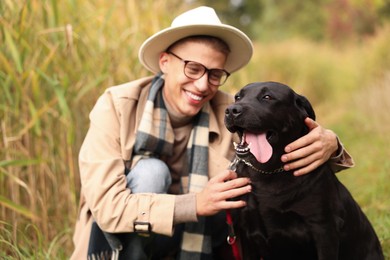 Smiling man with cute dog outdoors, selective focus