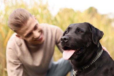 Photo of Portrait of cute dog with smiling owner outdoors, selective focus