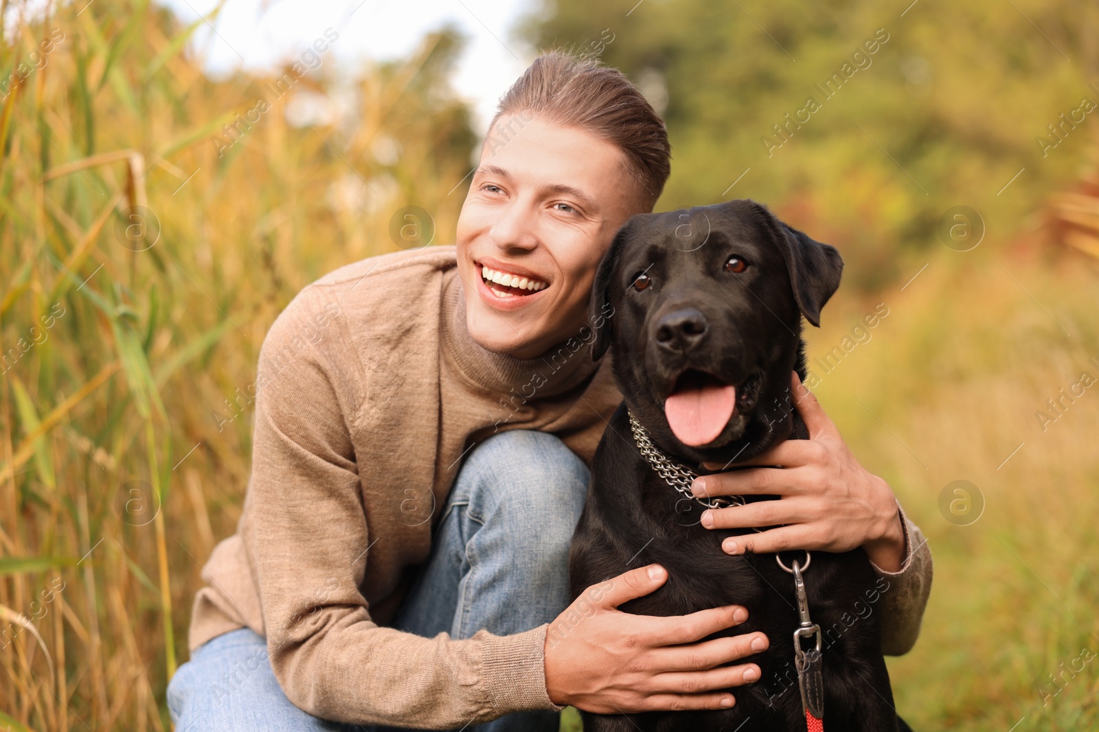 Photo of Smiling man with cute dog outdoors on autumn day