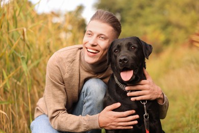 Photo of Smiling man with cute dog outdoors on autumn day