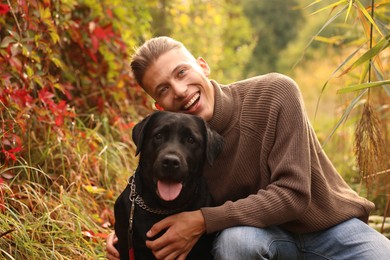 Smiling man with cute dog outdoors on autumn day. Space for text