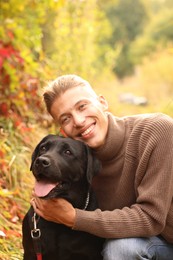 Photo of Smiling man with cute dog outdoors on autumn day