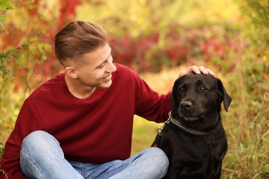 Smiling man stroking cute dog outdoors on autumn day