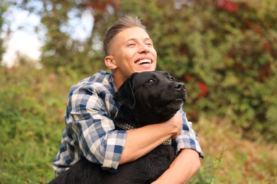 Photo of Smiling man hugging cute dog outdoors on autumn day