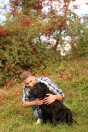 Smiling man hugging cute dog outdoors on autumn day. Space for text