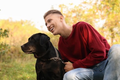 Photo of Smiling man with cute dog outdoors on autumn day