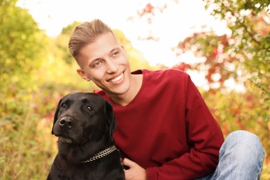 Photo of Smiling man with cute dog outdoors on autumn day