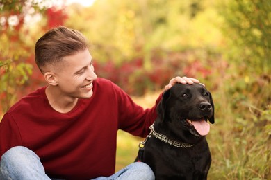 Photo of Smiling man stroking cute dog outdoors on autumn day