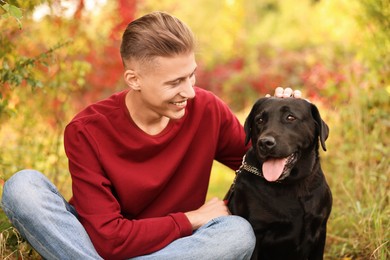 Smiling man stroking cute dog outdoors on autumn day