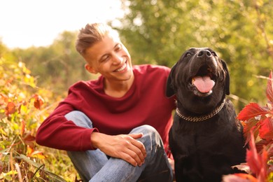 Photo of Smiling man with cute dog outdoors on autumn day, selective focus