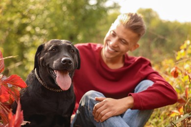 Smiling man with cute dog outdoors on autumn day, selective focus