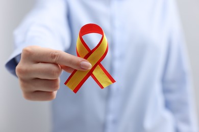 Photo of Woman with yellow and red ribbon on grey background, closeup. Hepatitis C awareness