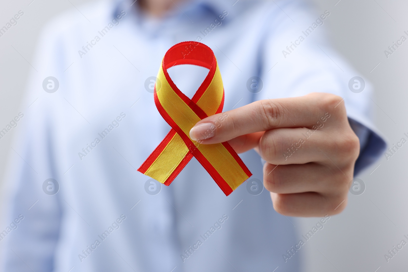 Photo of Woman with yellow and red ribbon on grey background, closeup. Hepatitis C awareness