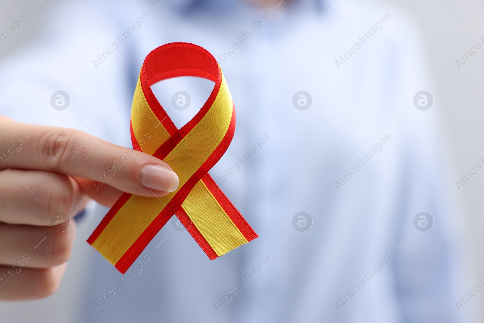 Photo of Woman with yellow and red ribbon on grey background, closeup with space for text. Hepatitis C awareness