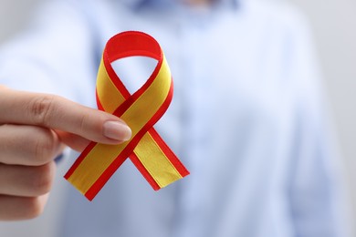 Woman with yellow and red ribbon on grey background, closeup with space for text. Hepatitis C awareness