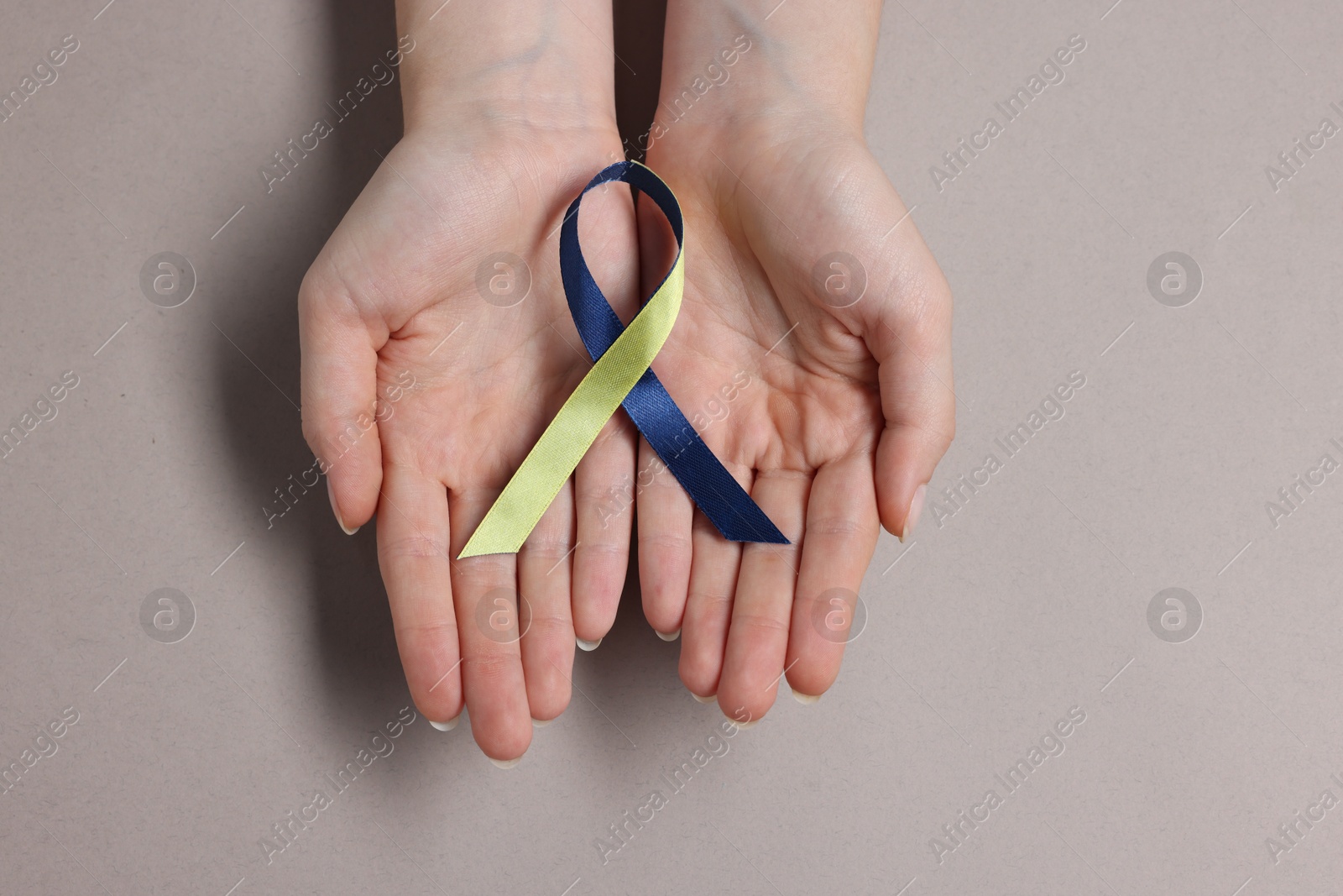 Photo of Woman with yellow and blue ribbon on grey background, top view. Down syndrome awareness