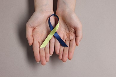 Woman with yellow and blue ribbon on grey background, top view. Down syndrome awareness