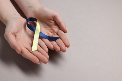 Photo of Woman with yellow and blue ribbon on grey background, closeup with space for text. Down syndrome awareness