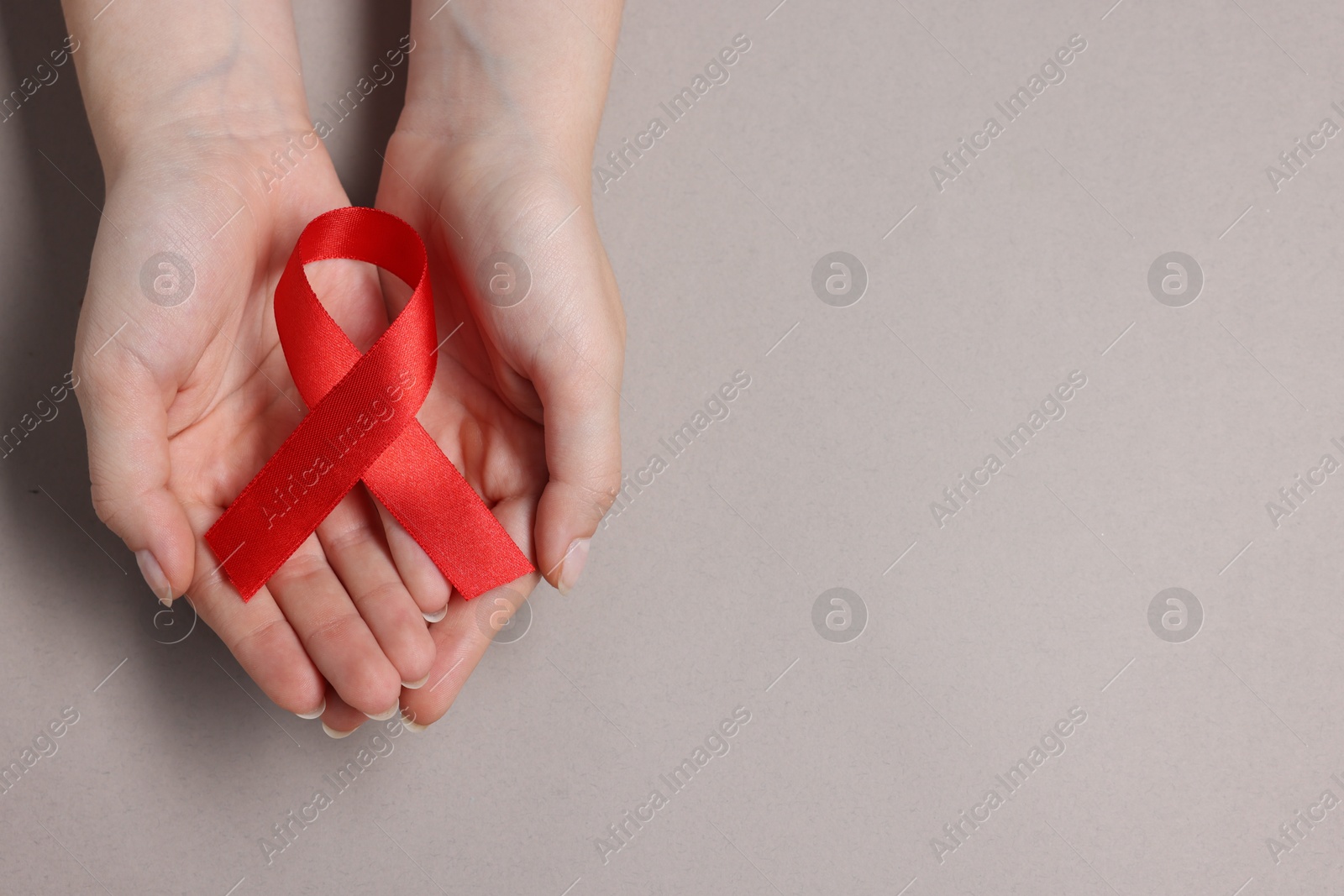 Photo of Woman with red ribbon on grey background, top view and space for text. HIV (AIDS) disease awareness