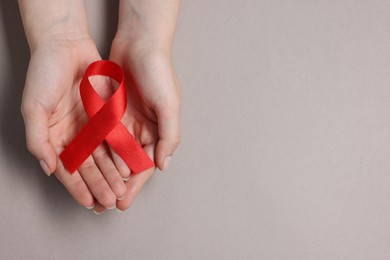 Photo of Woman with red ribbon on grey background, top view and space for text. HIV (AIDS) disease awareness