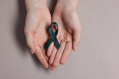 Woman with teal ribbon on grey background, top view. Ovarian cancer and gynecological disorders awareness