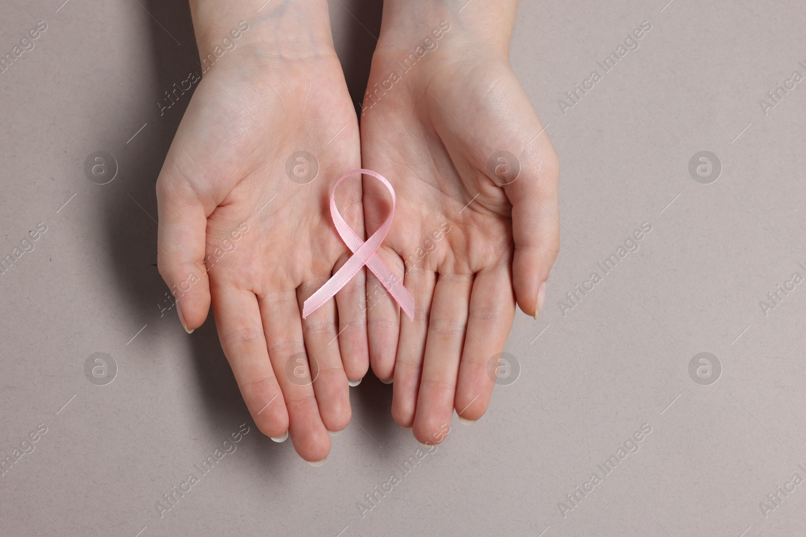 Photo of Woman with pink ribbon on grey background, top view. Breast cancer awareness