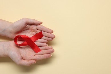 Photo of Woman with red ribbon on beige background, top view and space for text. HIV (AIDS) disease awareness