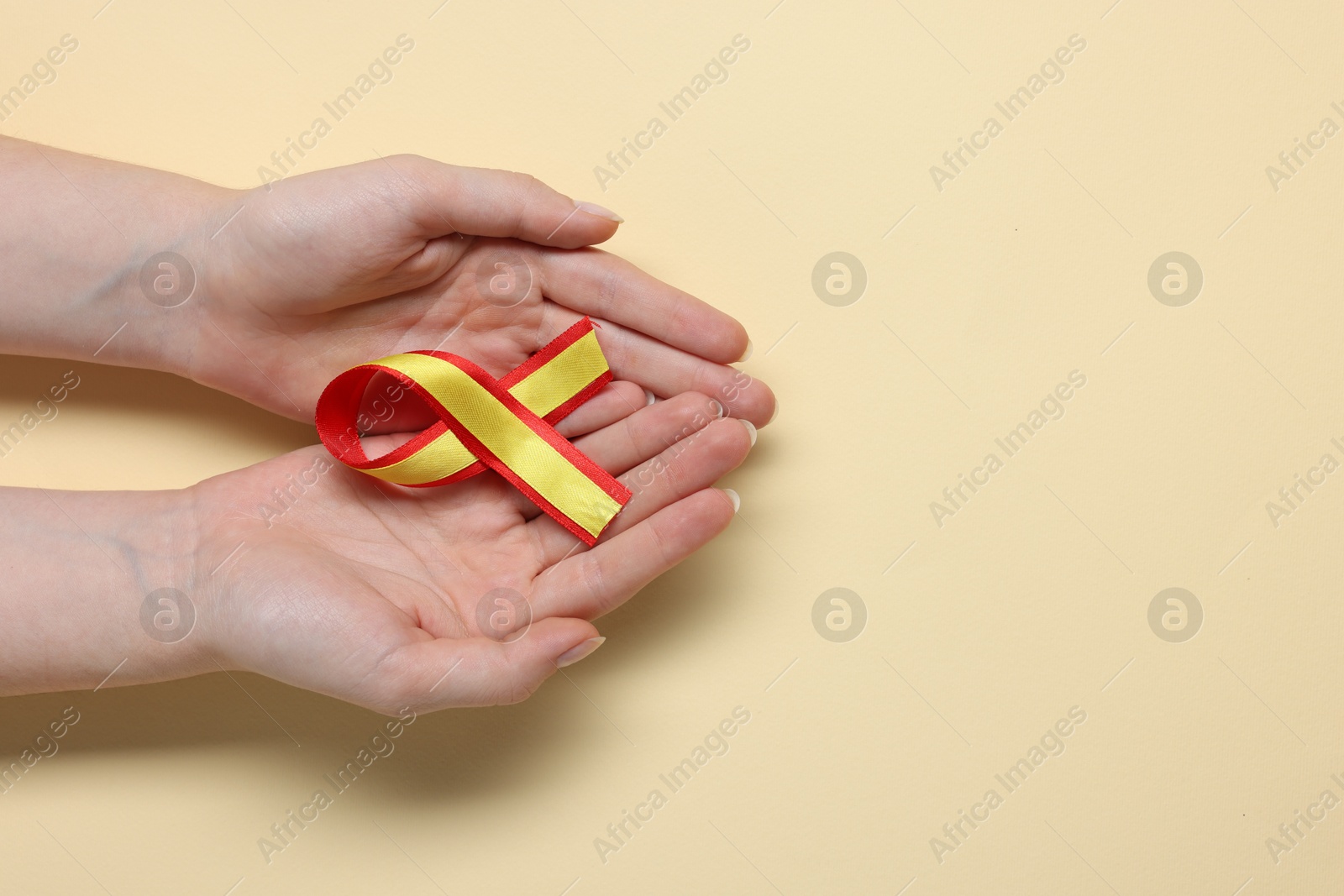 Photo of Woman with yellow and red ribbon on beige background, top view with space for text. Hepatitis C awareness