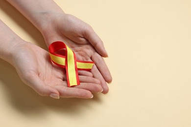 Photo of Woman with yellow and red ribbon on beige background, top view with space for text. Hepatitis C awareness