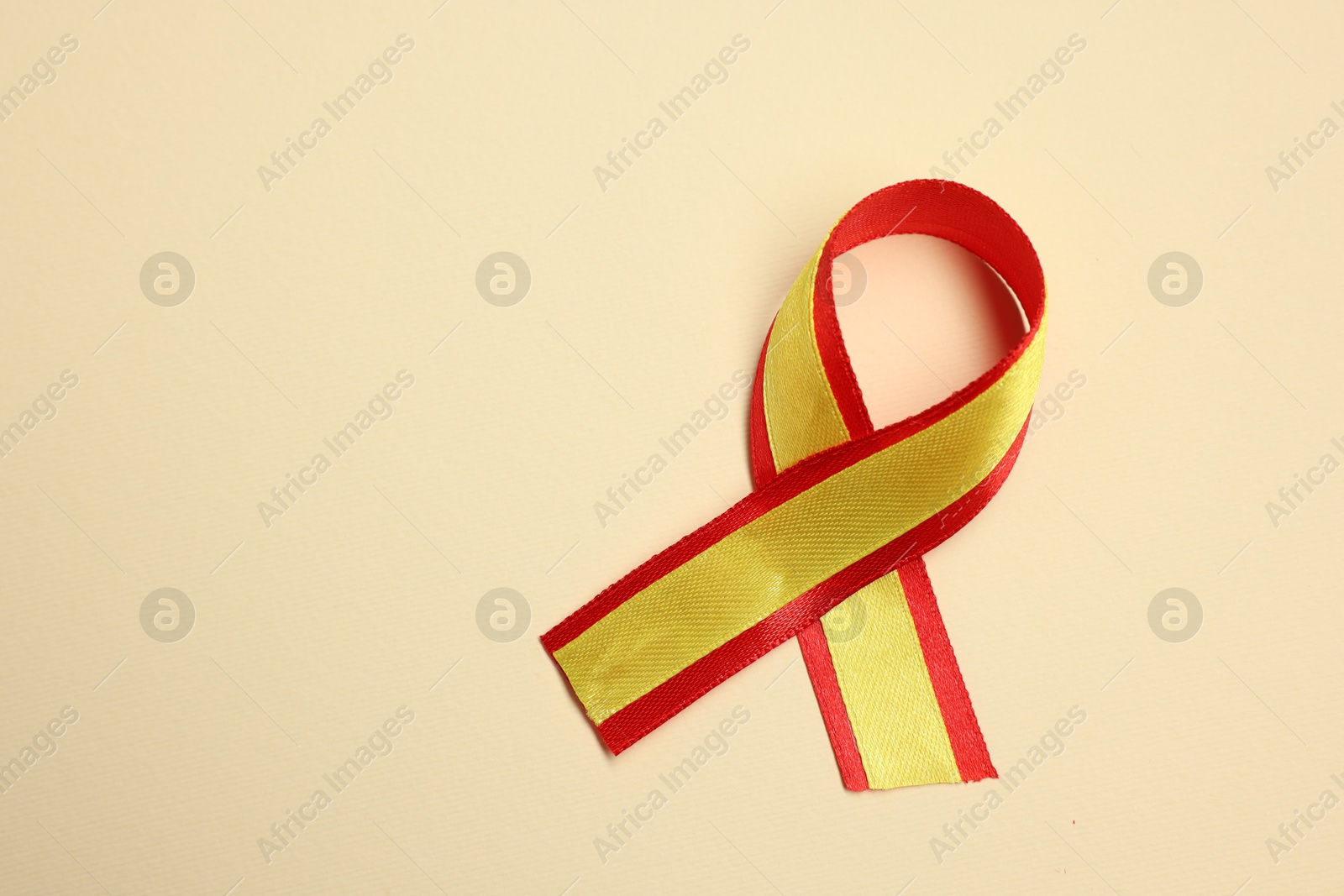 Photo of One yellow and red ribbon on beige background, top view with space for text. Hepatitis C awareness