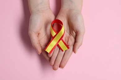 Photo of Woman with yellow and red ribbon on pink background, top view. Hepatitis C awareness