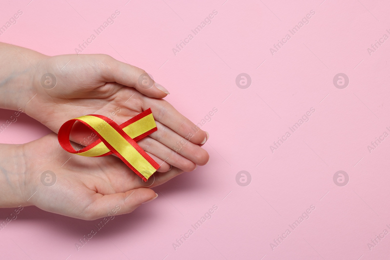 Photo of Woman with yellow and red ribbon on pink background, top view with space for text. Hepatitis C awareness