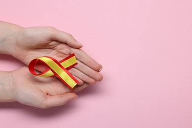 Photo of Woman with yellow and red ribbon on pink background, top view with space for text. Hepatitis C awareness