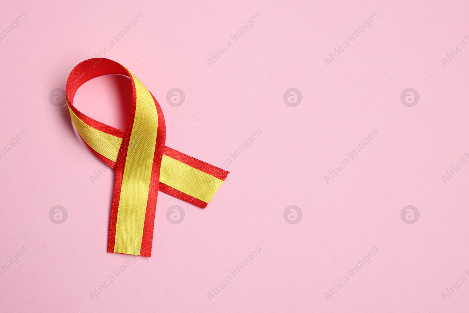 Photo of One yellow and red ribbon on pink background, top view with space for text. Hepatitis C awareness