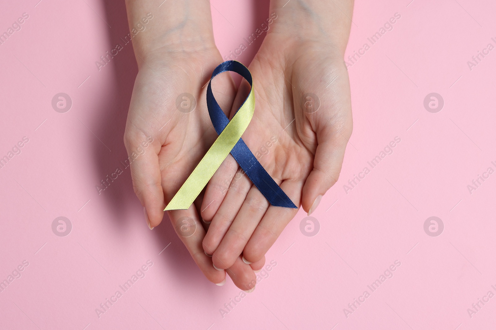 Photo of Woman with yellow and blue ribbon on pink background, top view. Down syndrome awareness