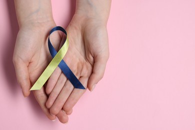 Photo of Woman with yellow and blue ribbon on pink background, top view with space for text. Down syndrome awareness